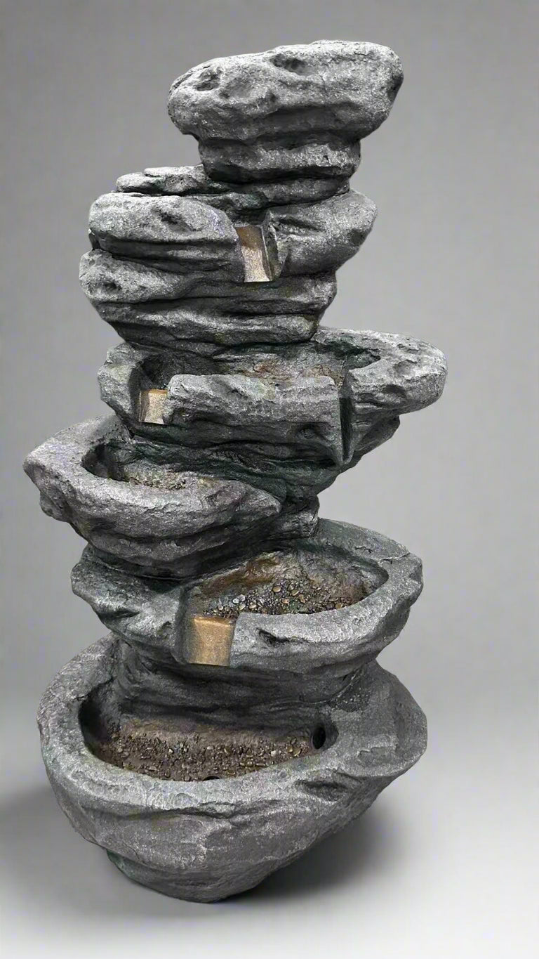 Stacked stone fountain on a concrete floor with a dark background