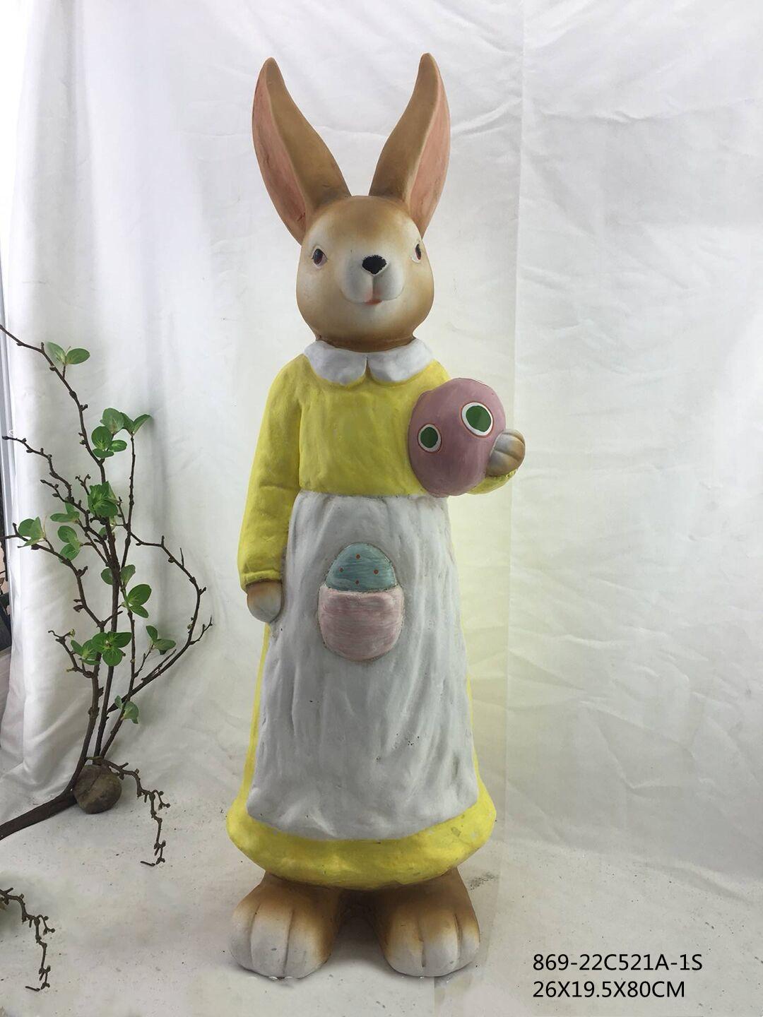 Plush toy rabbit in a yellow dress holding a pink flower against a white background