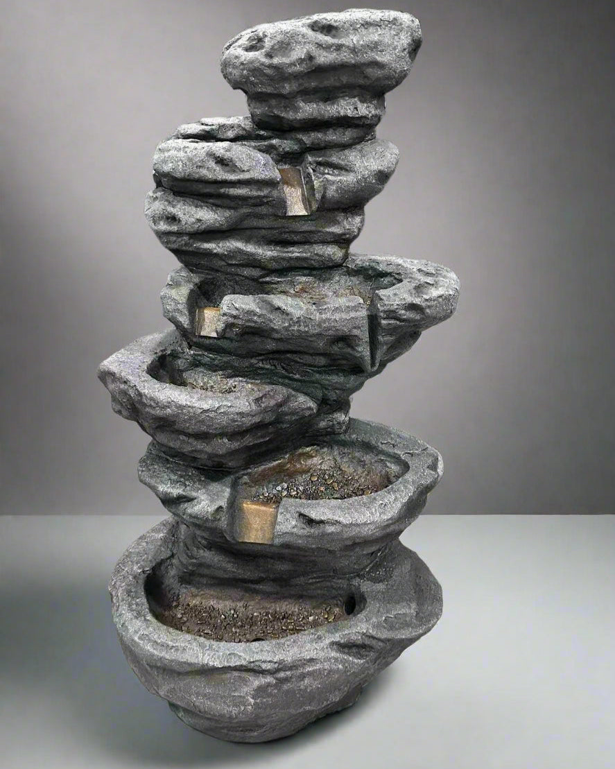 Stacked stone fountain on a concrete floor with a dark background